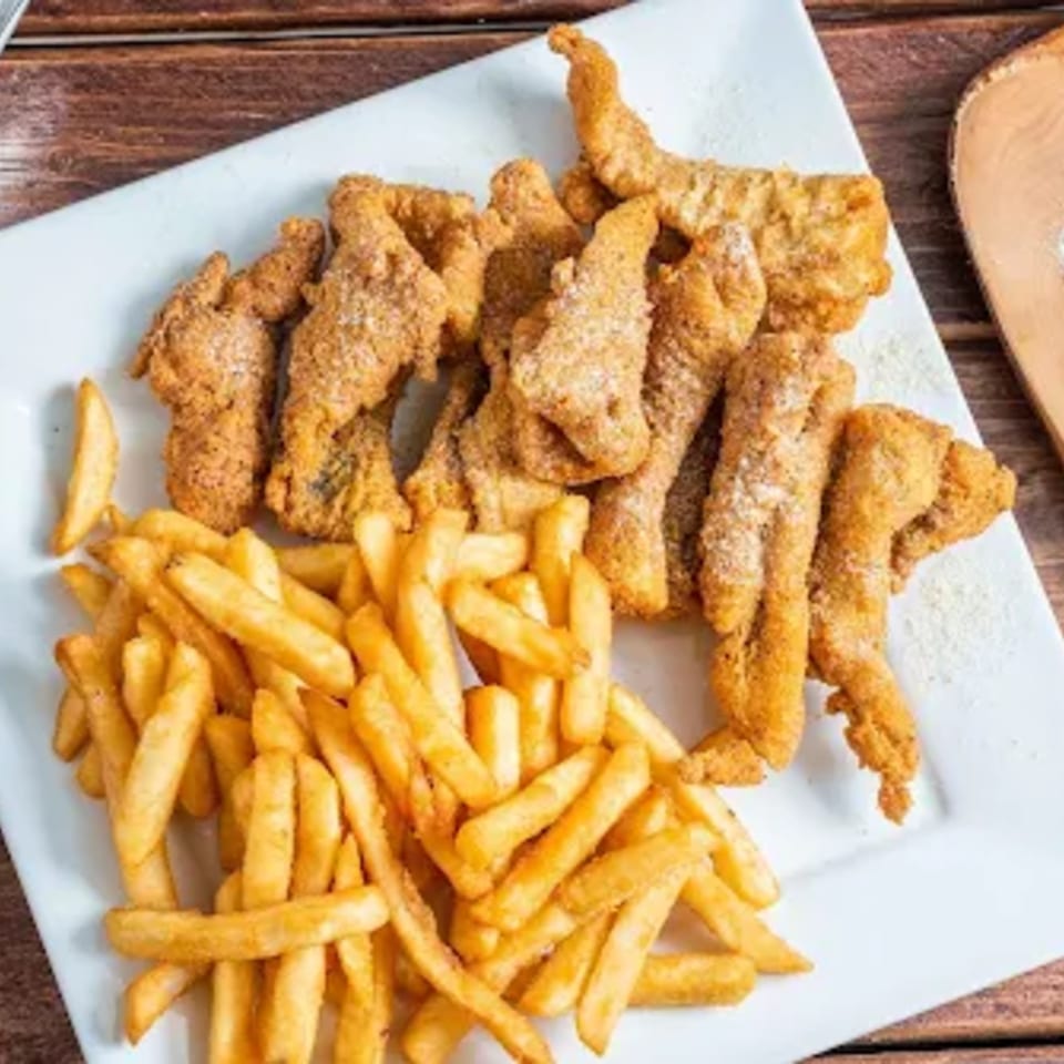 Crispy fried chicken tenders and golden french fries on a white rectangular plate from Times Square Kitchen.