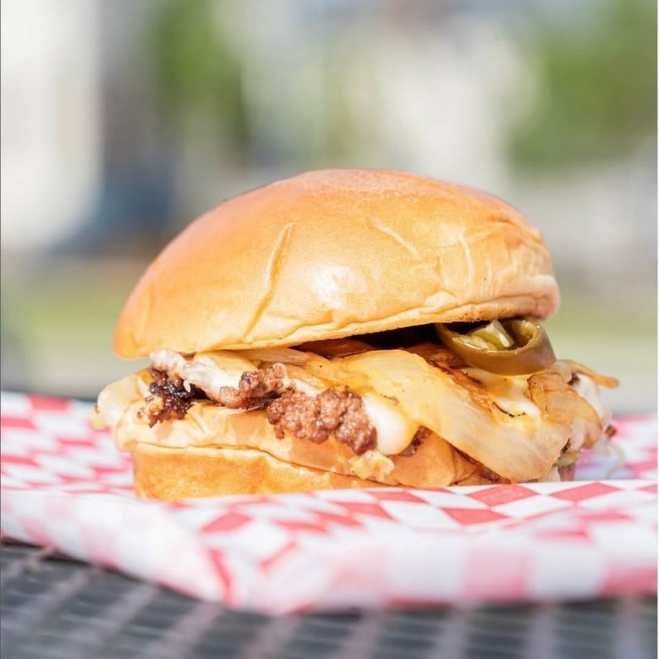 A Times Square Kitchen burger with chili, melted cheese, grilled onions, and jalapeños on a bun.